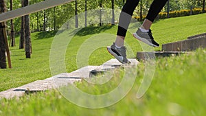 Close-up of the legs of a slender woman running up the stairs in the park.