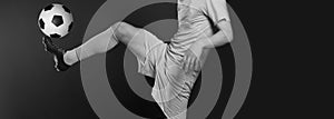 Close up legs and soccer shoe of football player in action kicking ball  on black background. Black and white filter