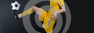 Close up legs and soccer shoe of football player in action kicking ball  on black background wearing yellow jersey and