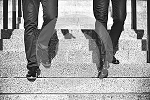 Close up legs of two businessman walking down stair in modern city