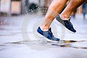 Close up of legs of unrecognizable runner, town, puddle