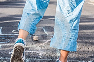 Close up of legs of a woman jumping and playing at hopscotch - portrait of lady having fun jumping on the asphalt