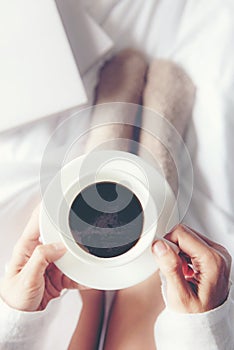 Close up legs women on white bed. Women reading book and drinking coffee in morning relax mood