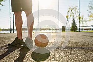 Close up of legs of young male basketball player in sportswear standing on the court with basketball during Covid19