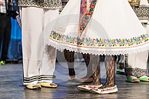 Close up of legs of young Romanian dancers perform a folk dance in traditional folkloric costume. Folklore of Romania