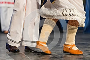 Close up of legs of young Romanian dancers perform a folk dance in traditional folkloric costume. Folklore of Romania