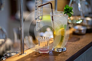 the lemonade drink with ice in a clear glass beside a glass tube and the laboratory, adjust the flavor to the right,