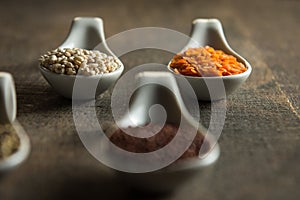 Close up of lentils and quinoa in white spoons on wood