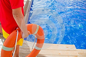 Close-up of a lifeguard`s hand grabbing a lifebuoy ring and watching over a swimming pool - Concept of lifeguard at work