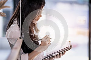 Young woman standing and making notes to her diary