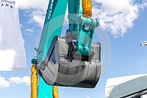 Close-up of lifted bucket of Sunward excavator against the background of the cloudy sky. Construction equipment fair