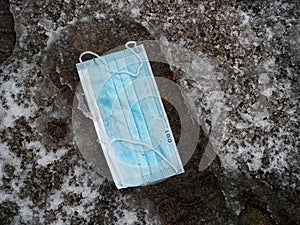 CLOSE UP: Light blue surgical masks falls into a footprint in the snow slush.