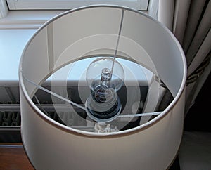 The close up of light bulb inside hotel table lamp.