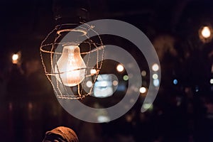 Close up light bulb with ropes in dark place. Retro style with bokeh