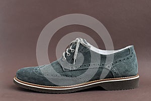 Close up of light green suede derby shoes on brown background