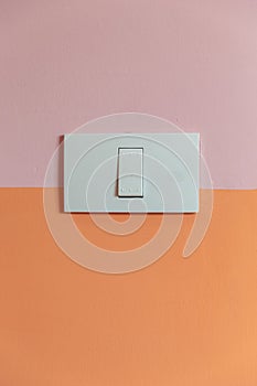 Close up of white Light Switch with copy space on pink and orange wall.
