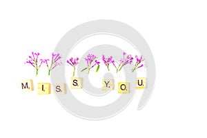 Close up of of lilac flowers and wooden letters forming - miss you on white background. Top view. Concept of love and
