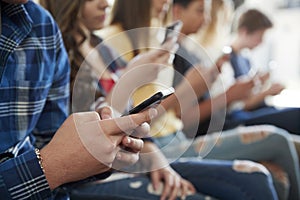 Close Up Of A Line Of High School Students Using Mobile Phones