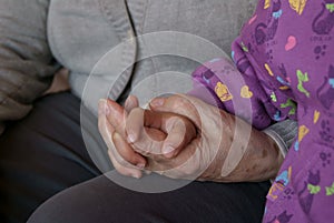 Close-up linked hands of girl and old woman