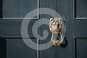 Close up of a lion`s head door knocker on a black door