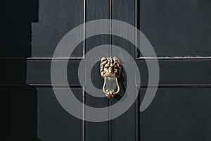 Close up of a lion`s head door knocker on a black door