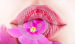 Close-up lips and flower. Close-up beautiful female lip with bright lipgloss makeup. Spa and cosmetics. Lips with