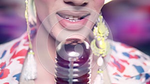 close-up of lips. male travesty artist singing into microphone on stage in safita light