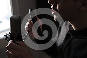 A close-up of lips at the microphone of a singing young man standing