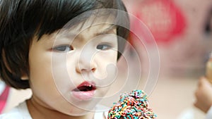 Close up of little Asian baby girl enjoyed eating chocolate icecream with rainbow toppings - baby`s development on their feeling