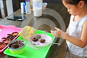 Close up little Asian kid girl in process class of homemade chocolate donuts