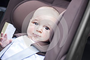 Close up of little baby boy in a car in a child seat