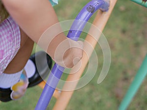 Close up of little baby`s hand holding on a metallic stairs at a playground learning to climb it up