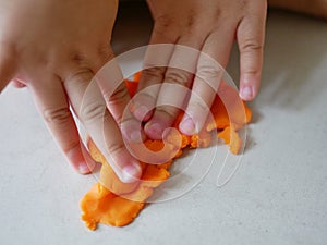 Close up of little baby`s hands massaging playdough on the house floor