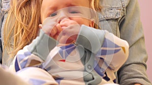 Close-up of little baby`s legs in pajamas sitting on hands at mum