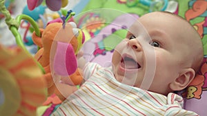 Close up of little boy face. Portrait of happy baby on colorful mat with toys