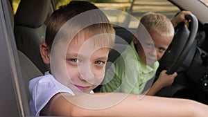 Close-up of a little boy with his brother sitting in the car at the wheel.