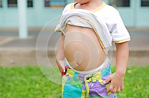 Close up little boy lifting his shirt show exposing his big tummy