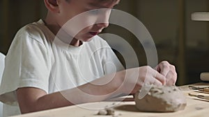 Close up of little boy plays with clay in pottery class