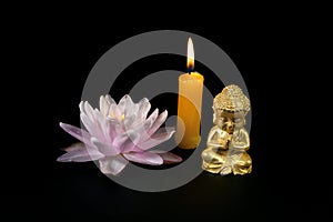 Close-up of a little Buddha statue, water lily, and burning candles