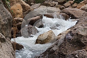 Close up of a little cascade falls of water over mountain river rocks