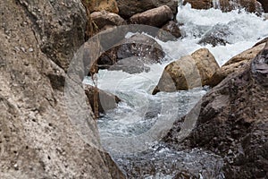 Close up of a little cascade falls of water over mountain river rocks