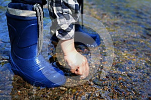 CLOSE UP OF LITTLE CHILD WEARING BLUE RAINBOOTS AND PLAYING WITH photo