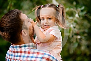 Close-up of little cute girl smiling in the arms of her father.