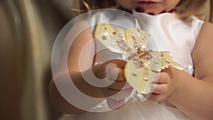 Close-up of a little girl fiddles with golden butterfly