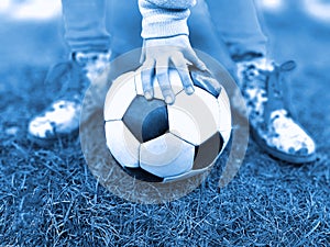 Close up little girl hand hold soccer ball on green grass.
