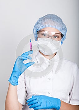 Close-up little girl in a medical dress and gloves holding a syringe