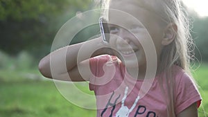 Close-up of a little girl with a mobile phone in her ear