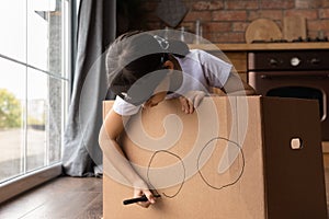 Close up little girl playing pirate, drawing on cardboard box