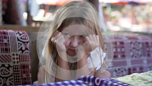 Close-up, a little girl with a sad face waiting for an order in a restaurant