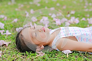 Close up little girl sleeping on green grass with fall pink flower in the garden outdoor